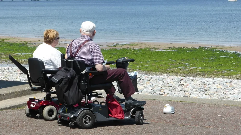 Twee scootmobielen onderweg op een pad langs de kust