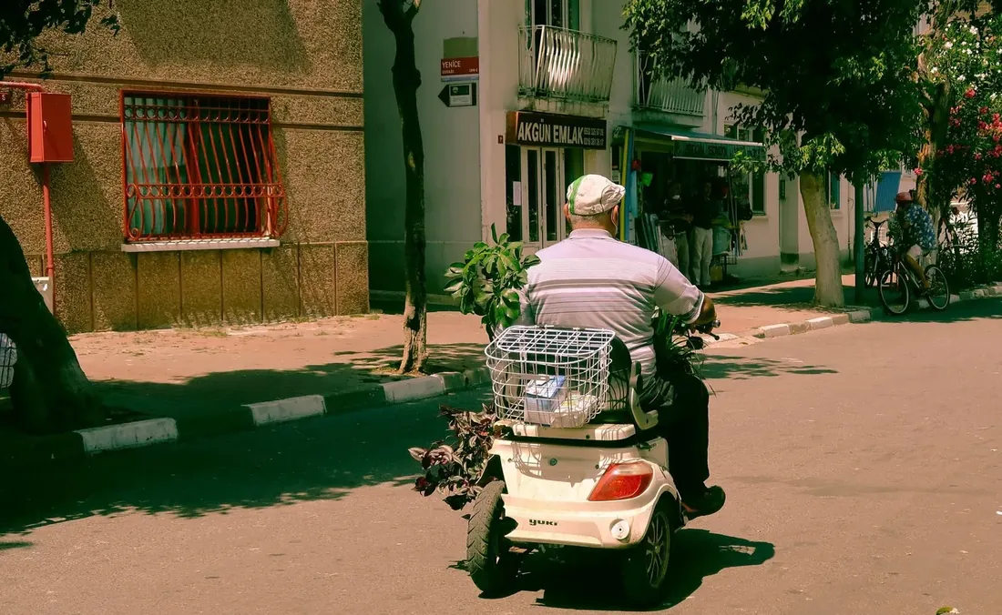 Senior rijdt zelfstandig op een scootmobiel door een Amsterdamse straat