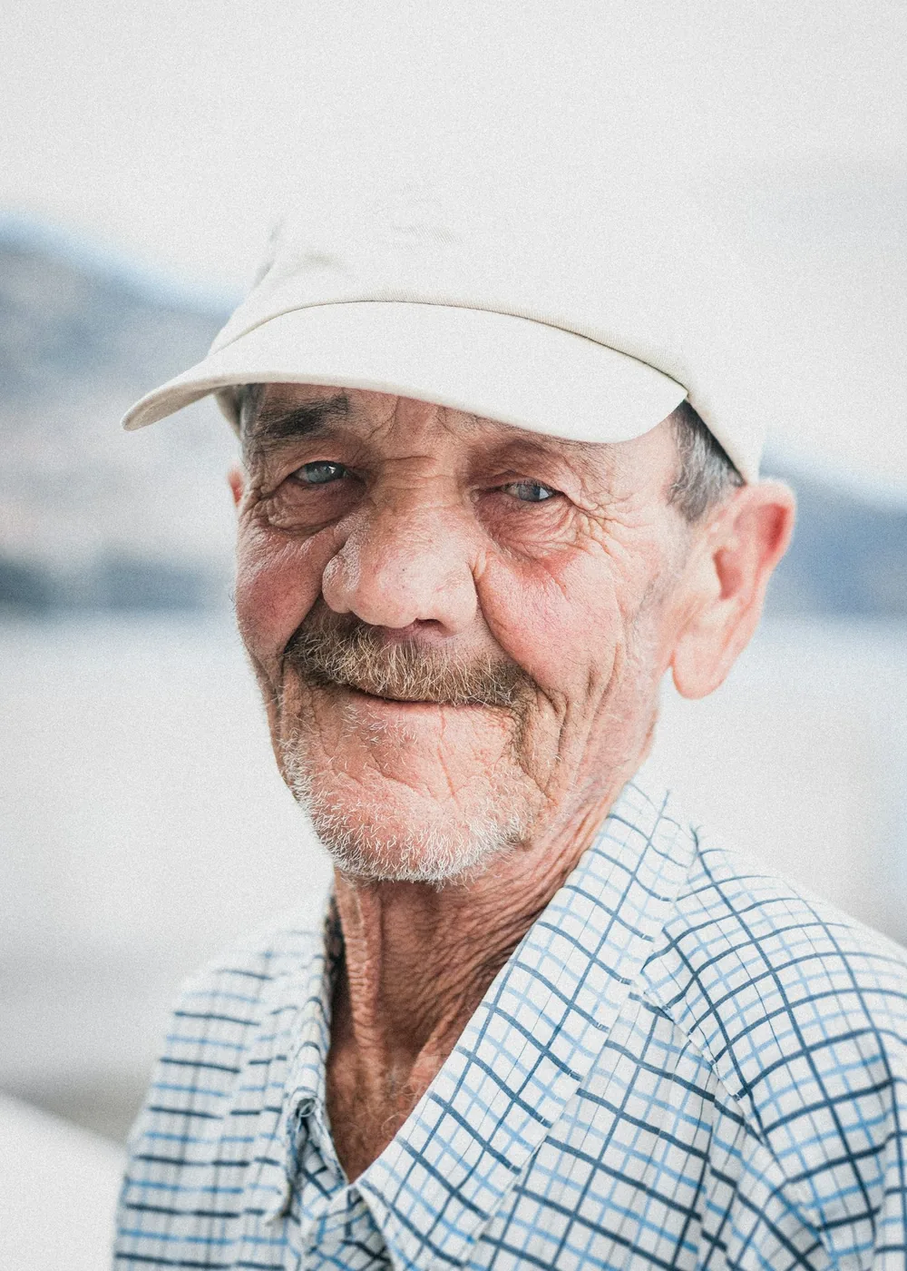 Warm portret van een glimlachende oudere man met pet